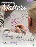 MaineGeneral Health's Philanthropy Matters Winter 2022 front magazine cover. Headlines: Hope is here to stay. Together we believe. Feeling the love of our community. Image shows an older man writing a note of support for a cancer fighter on a large poster