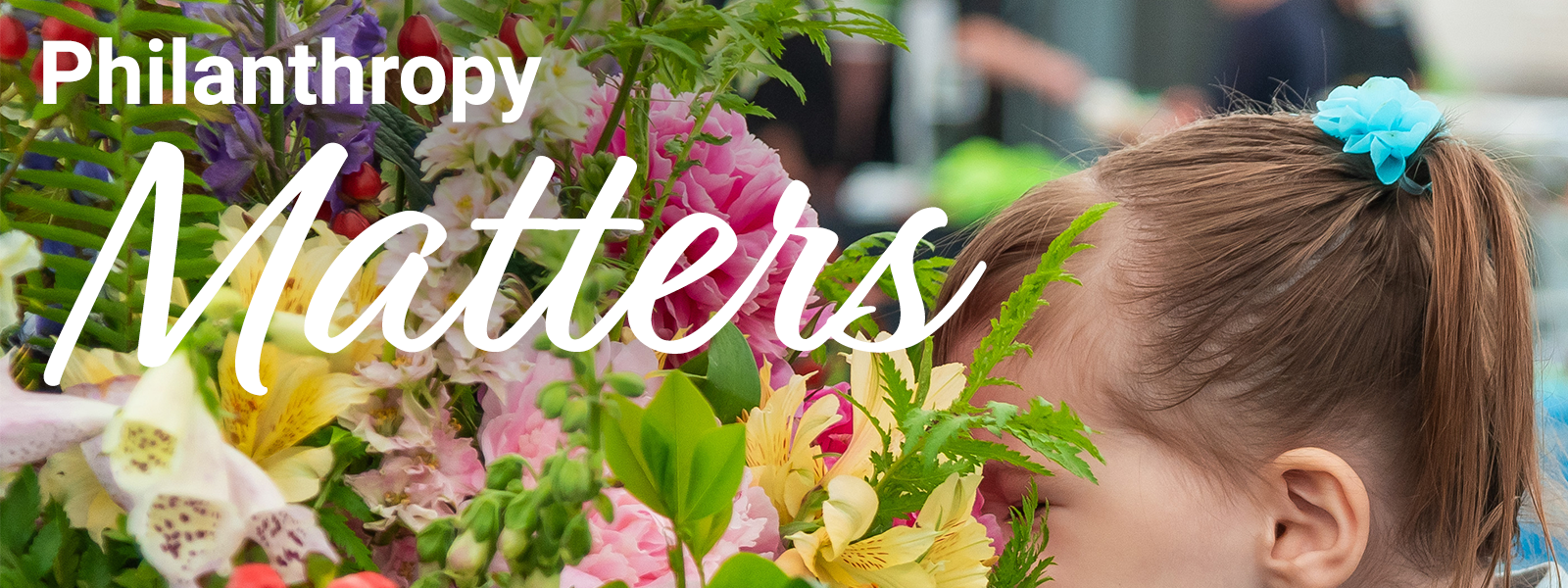 MaineGeneral Health's Philanthropy Matters Summer 2023 front magazine cover. A young child leans forward to breathe in the scent of a brightly-colored floral arrangement.